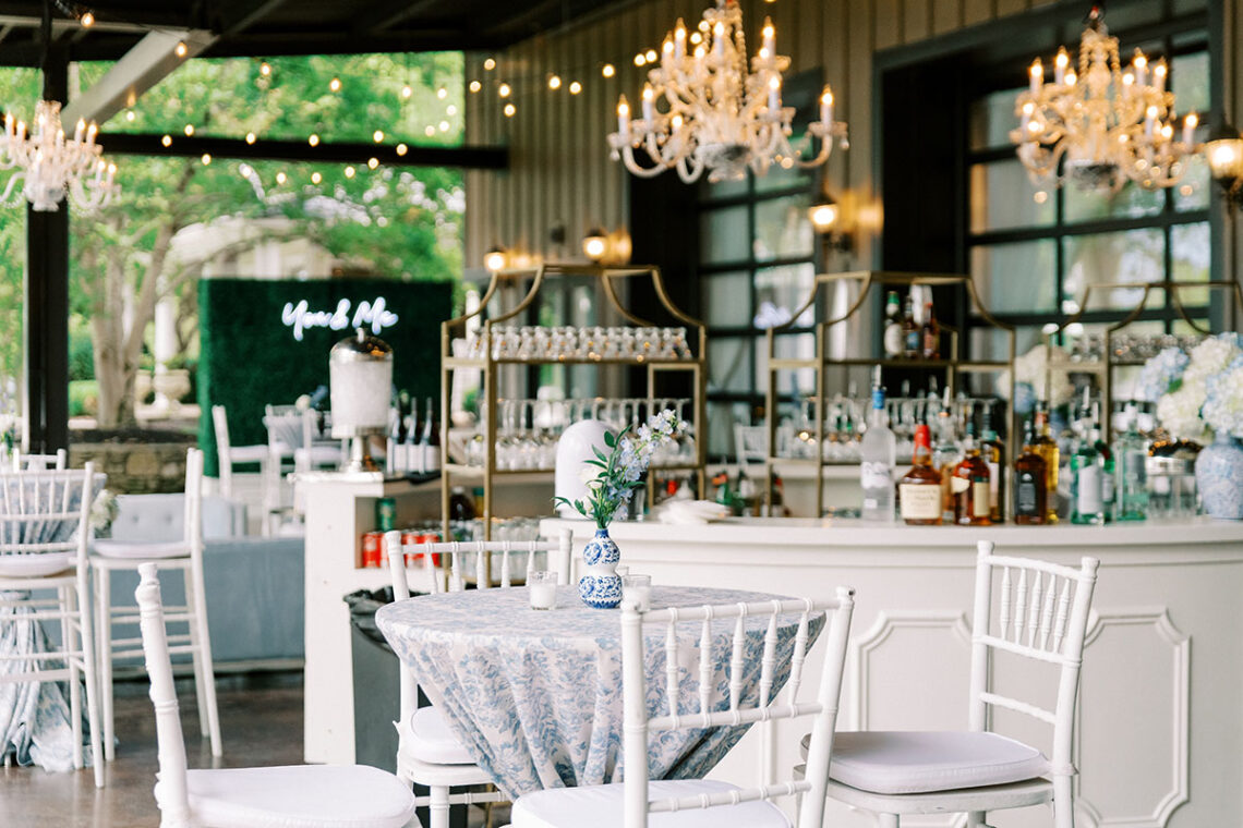 Exterior patio setup with white bar and bistro tables dressed in French blue linens