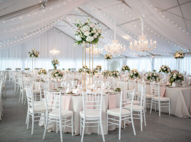 Sunset Terrace wedding reception with neutral linens, white chairs, crystal chandeliers, and romantic arrangements with pastel roses and white hydrangeas