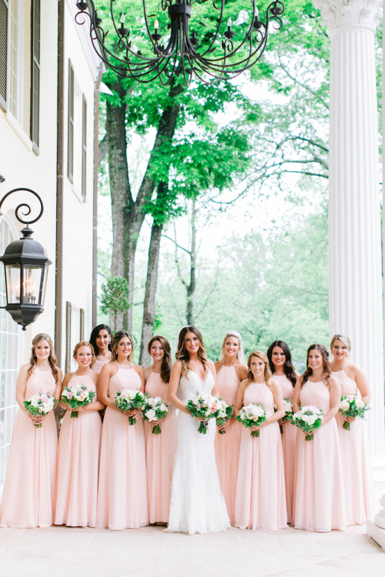 Bride with bridesmaids in pink dresses on mansion's steps
