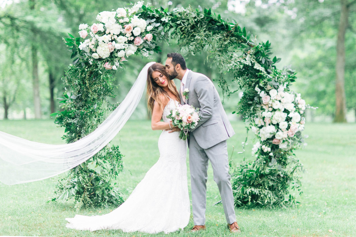 Bride and Groom in front of round greenery ceremony arch