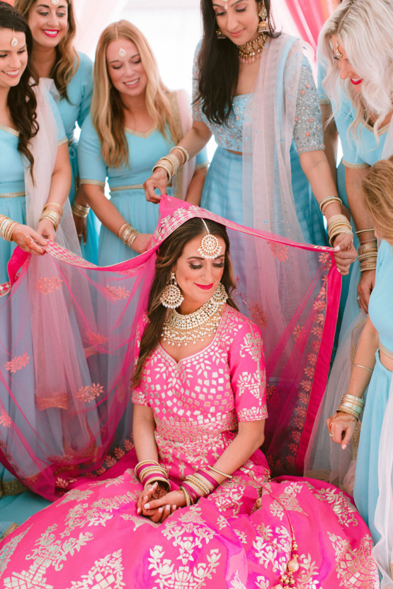 Bride in traditional Indian dress in hot pink with bridesmaids in blue