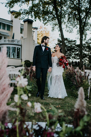 bride and groom walk hand in hand down aisle line with floral arrangements