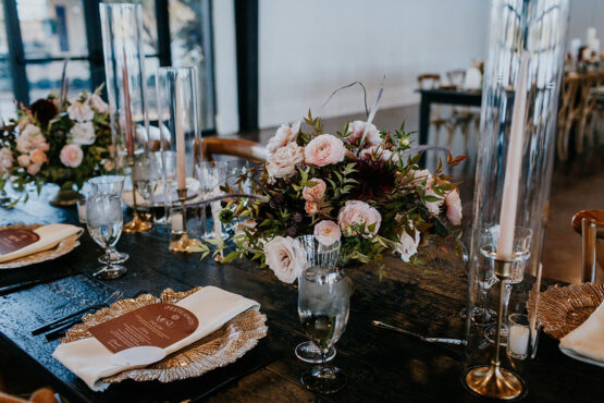 close-up of wedding tablescape with gold charger table setting with custom printed menu and moody floral arrangements with pastel pink blooms