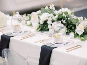 Single cakes for Bride and Groom under mini cake stands on white table with white floral arrangements