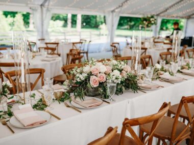 Tablescape for wedding reception on Sunset Terrace with large rose floral arrangement and tape candles with crystal classware