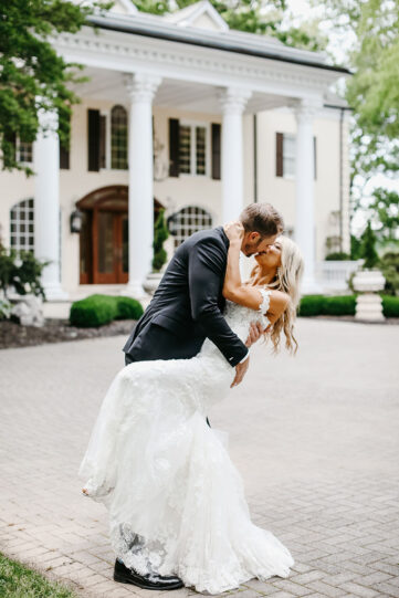 Bride and groom kissing in front of the Estate at Cherokee Dock