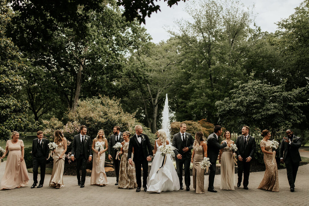 Bride and groom with wedding party in front of mansion's fountain