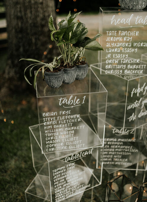 Modern eclectic seating charts on acrylic boxes with plant decor