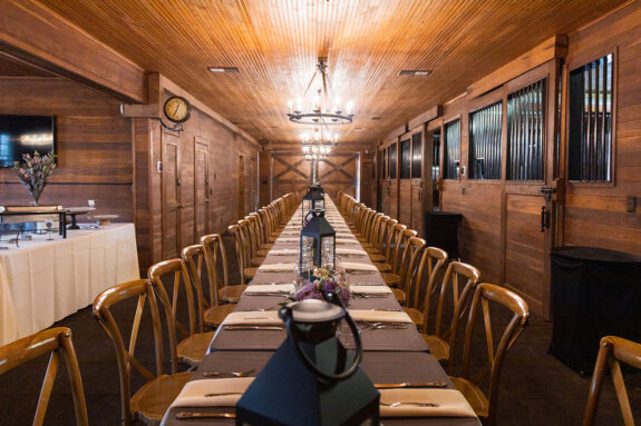 Long farmhouse table set up for rehearsal dinner in the Carriage House Stables