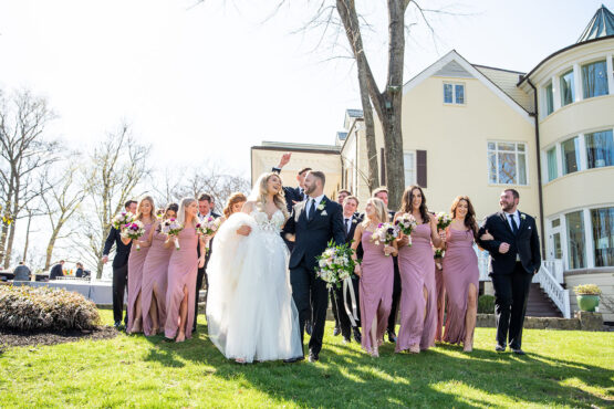 Wedding party portrait in front of The Estate at Cherokee Dock Large Wavy Bridal Hairdo with Spring Bouquet and Lace Wedding Dress