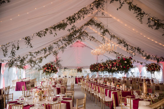 extravagant tented multicultural wedding reception with white draping, string lights, and greenery