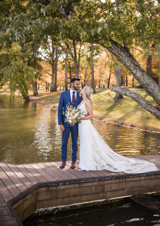 bride and groom pose on the lakeside dock