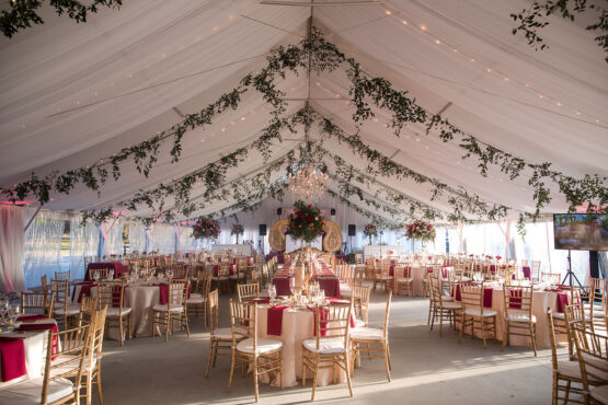 extravagant tented multicultural wedding reception with white draping, string lights, and greenery