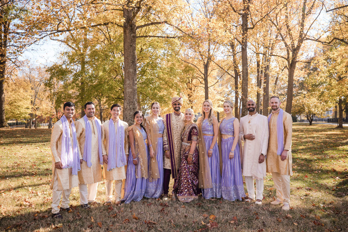 hindu wedding party poses under fall foilage at the estate at cherokee dock