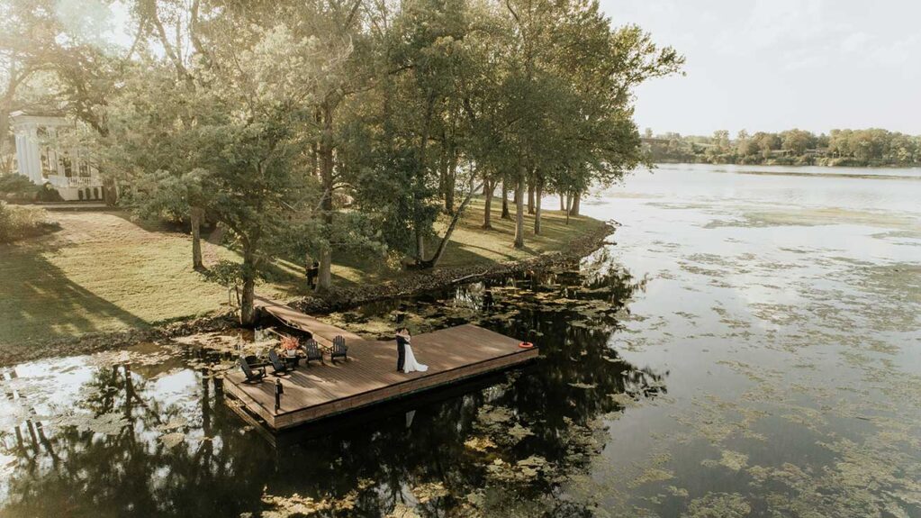 Bride and Groom Standing On Dock of luxury lakeside wedding venue with a view