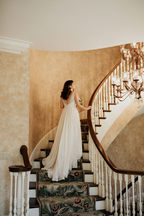 Bride Walking Up Grand Spiral Staircase inside mansion wedding venue