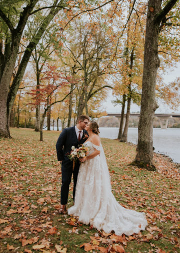 bride and groom pose amongst the fall foliage at the estate at cherokee dock on the lakeside lawn