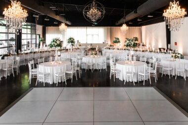 All white wedding reception setup inside Lakeview Event Center with chandeliers and dance floor