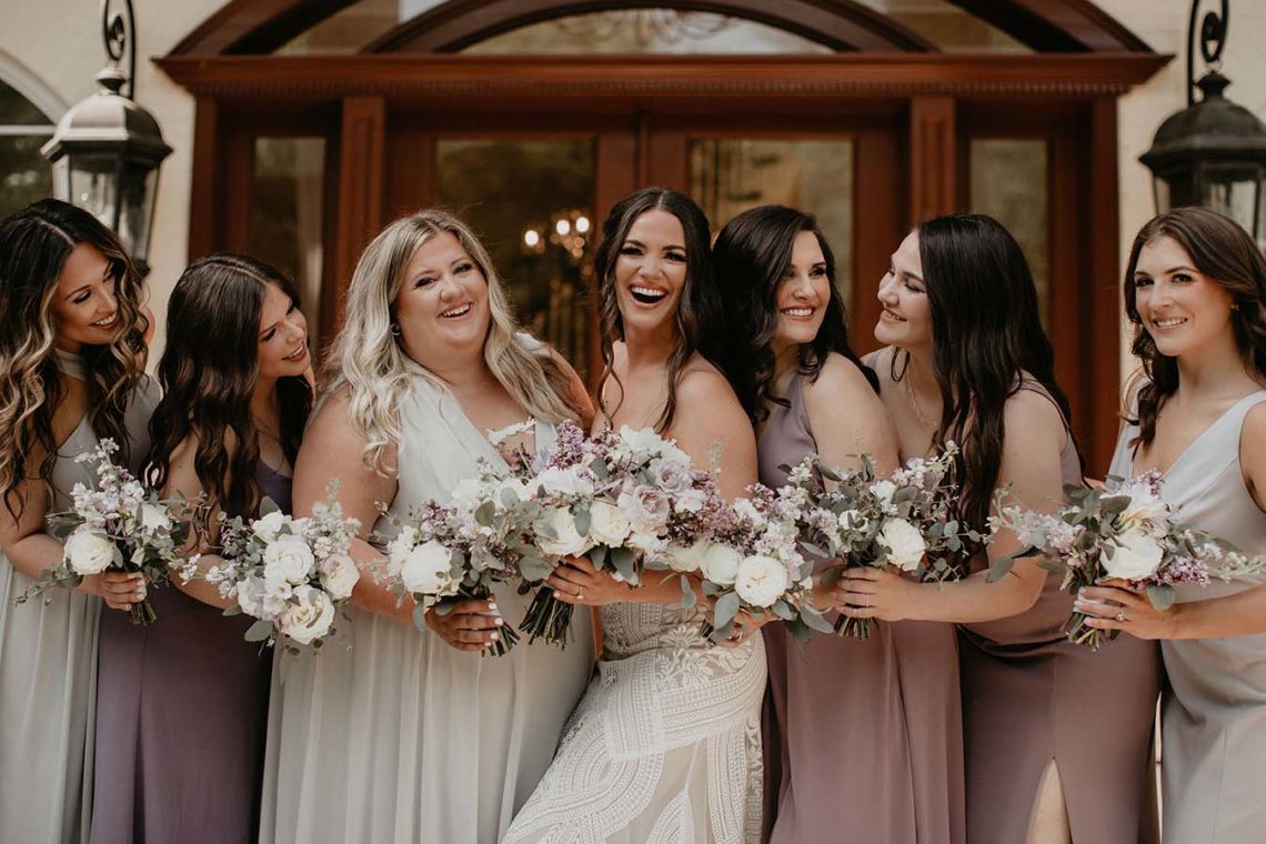 Hannah and her bridesmaids smile joyfully for a photo on the front porch of the estate at cherokee dock