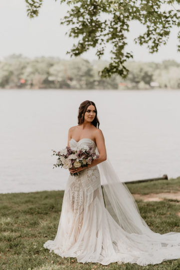 Hannah elegantly poses for a photo in front of lake in her Dress Theory gown