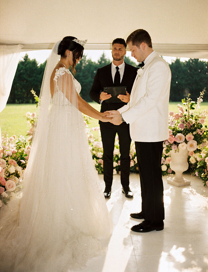 Southern princess bride and groom in white tuxedo during tented wedding ceremony