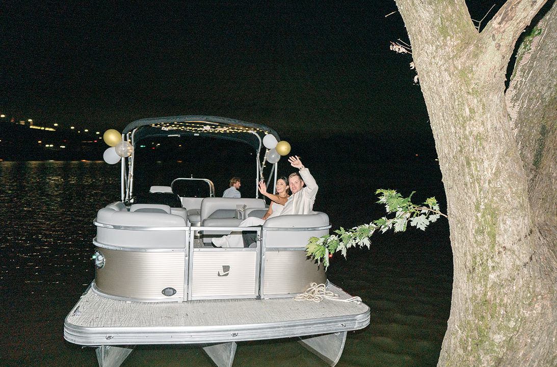 Bride and groom leave on a pontoon boat