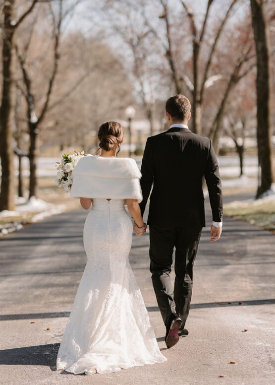 bride and groom walk down the drive hand and hand