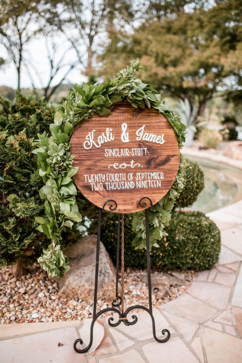 Wedding welcome sign created with greenery and round wood plaque