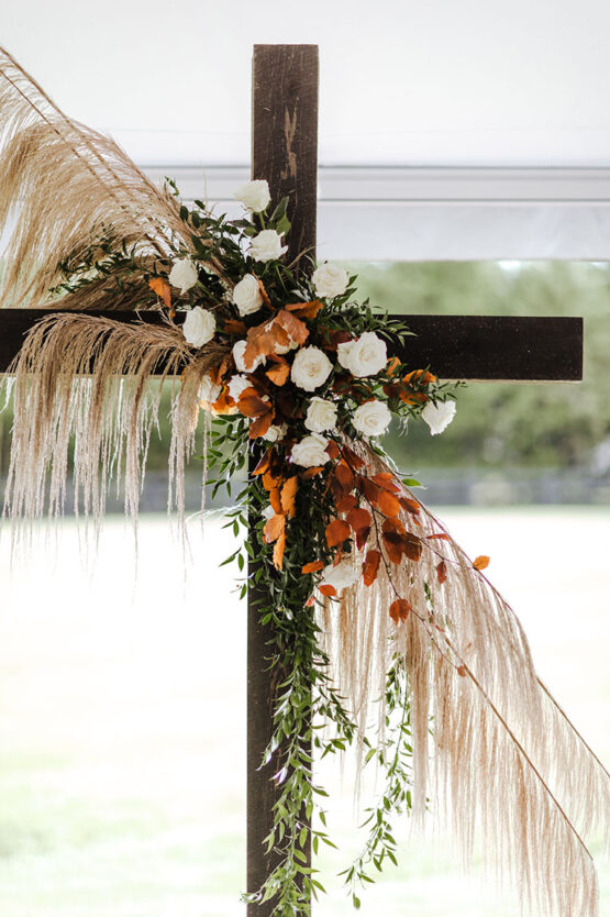 Dark Wooden Ceremony Cross with Rust Autumn Leaves White Roses and Greenery | Boho Fall Wedding Inspiration | The Estate at Cherokee Dock