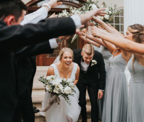 Laura and Mark walking under hands of wedding party and cheering