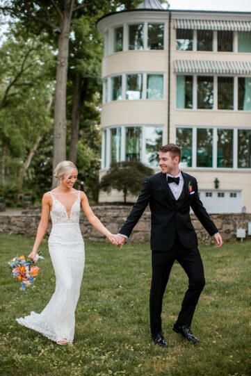 Mackenzie and Austin walk hand in hand in the backyard of the Estate at Cherokee Dock