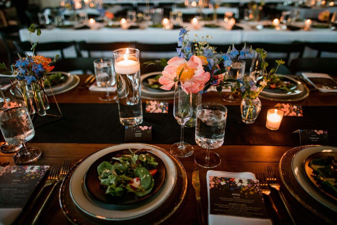 Kings table setting with black runner, candle lighting, and bright florals