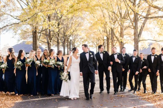 madison and colton with their wedding party walking down the drive
