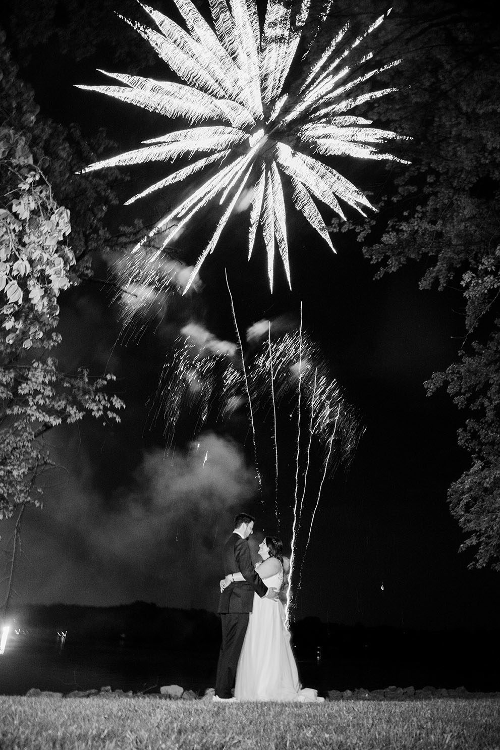 bride and groom ebrace as fireworks go off around them
