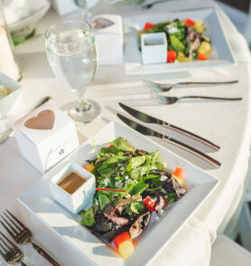 Plated salad sitting on table with white linens