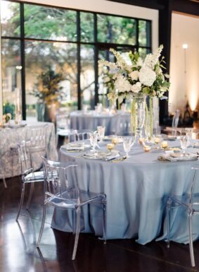 Wedding reception tables with blue linens and acrylic chairs inside Lakeview Event Center