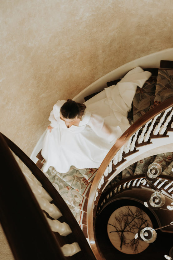 bride walking down spiral stairs in the mansion
