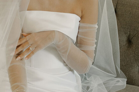 Editorial-style cropped shot of the bride with her sleeveless dress and full-length sheer gloves