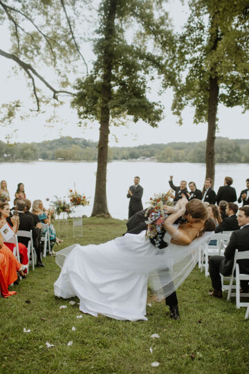 The groom dips his bride for a kiss as guests cheer while they leave their wedding ceremony during the recessional