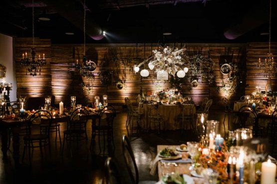 Wedding reception inside Lakeview Event Center with low lighting, eclectic chandeliers and boho table decor