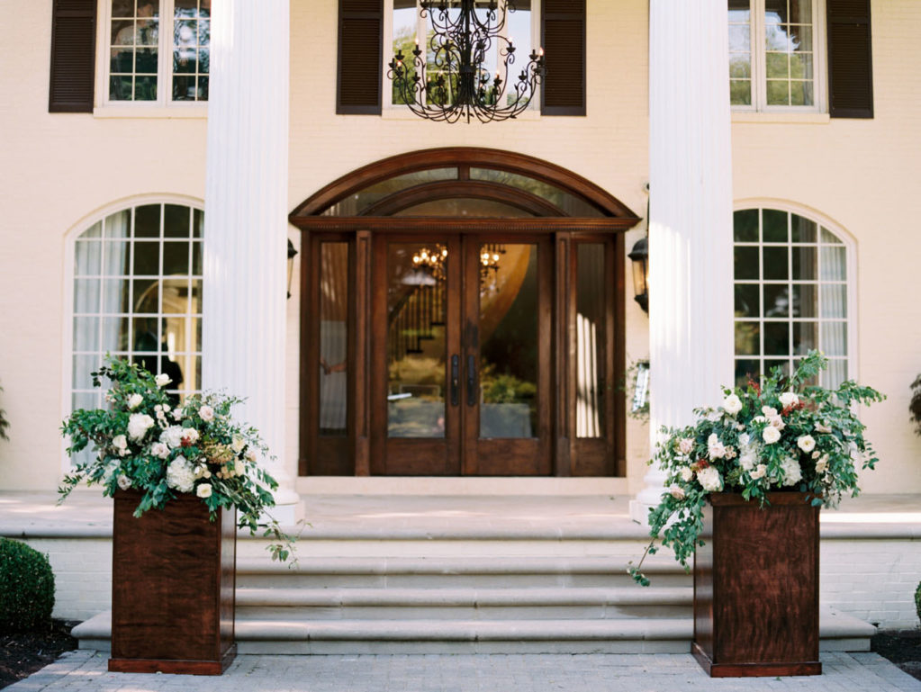 Mansion's front steps and doors with greenery-filled altar arrangements