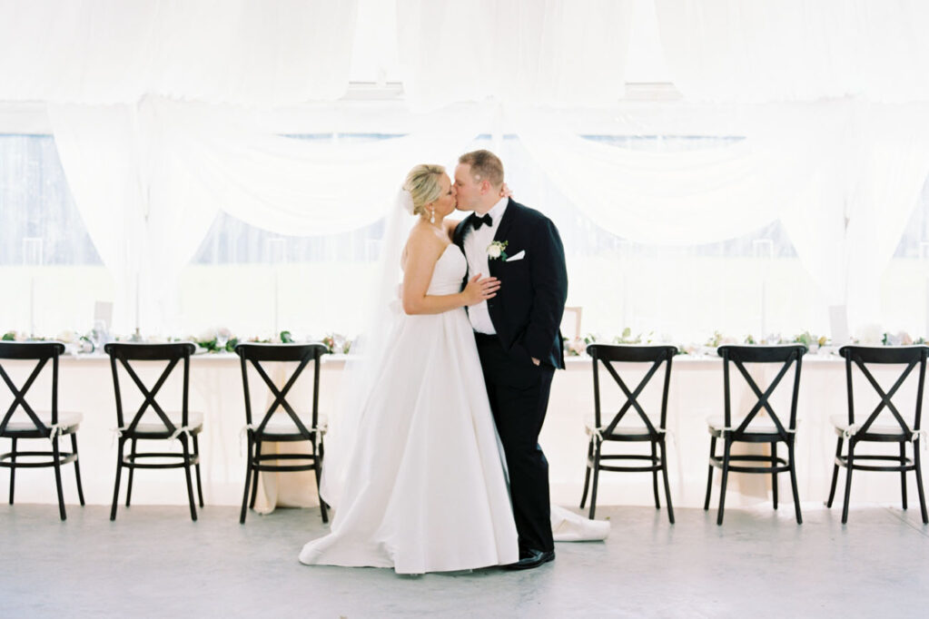 Bride and groom kissing in front of reception table on Sunset Terrace