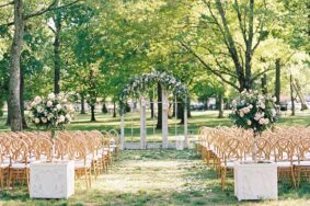 Wedding ceremony setup under Willow Oak Canopy with white flowers and vintage windows as ceremony backdrop