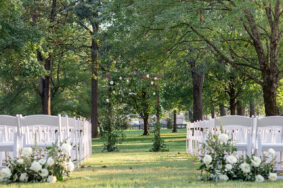 Wedding ceremony under the Willoa Oak Canopy with white chairs and classic wood arch with greenery decor